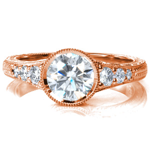 Intricate hand engraving is featured on the band which flares into the center setting. Graduated sizes of round brilliant stones lead up to the 0.70 carat bezel set round brilliant diamond in the center. Milgrain detail is added to the bright cut edges, the bezel, and the opening visible from the profile of the ring.