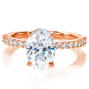 A 2 carat oval is set simply atop a charming shared prong band with round brilliant diamonds spanning half way around the ring. This classic style delivers lots of sparkle, and it is designed so that any wedding band design will sit flush against it. 