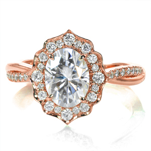 A 1.0 carat oval diamond is framed by a decorative, vintage-inspired halo and perched atop a cathedral setting. The delicate, twisted band alternates high polished metal with shimmering diamonds, creating a lovely texture and perfectly complementing the center setting. 