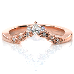 Perfectly contoured to fit around your engagement ring, this design has a vintage charm. A single pear shaped diamond creates the apex of the design, and small round diamonds lead down to the polished band. Rows of hand applied milgrain detail create the illusion of a twisted band. 