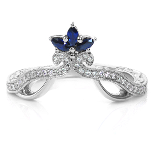 Feel like a princess in this stunning custom design! Marquise shaped royal blue sapphires sit atop swirling rows of bead-set diamonds. Hand applied milgrain detail frames the diamonds, and high polished metal scallops add interest. Relief engraved scrolls complete this unique wedding band.  