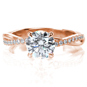 A glimmering 1 carat round brilliant diamond is showcased in a classic four prong setting. The narrow band intertwines, mixing a row of hand set diamonds and a row of high polished metal, adding texture and interest. This updated twist on a classic ring sparkles and shines from every angle. 