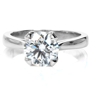 Understatedly elegant, this solitaire showcases a 1.5 carat round brilliant diamond in a classic four prong center setting. The cathedral setting tapers slightly toward the diamond, and the prongs open to reveal an alluring, tulip-inspired shape. The little details make all the difference! 