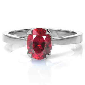 A rich oval cut ruby is held in four tulip-inspired prongs in this lovely, vintage inspired design. The high polished band tapers slightly into a cathedral setting. Open pockets are filled with hand-formed filigree curls, and decorative diamond petals are featured just under the center setting. 