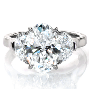 Why choose between an engagement ring and a statement piece when you can have both? A stunning 3.5 carat oval cut diamond is flanked by large half moon diamonds in a classic cathedral setting. Delicately draped baskets and claw prongs hold the diamonds securely in place, and a high polished band completes the design. 