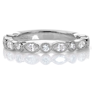 Perfect as a wedding band or a stacking ring, this design features alternating round brilliant and marquise shaped diamonds in full bezel settings. Each bezel is ornamented with hand applied milgrain detail, adding a touch of vintage flair and a lovely texture to this ring.  