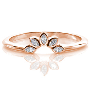 A delicate band engineered to curve around the center stone of an engagement ring, this design features five bezel set marquise diamonds arranged to look like brilliant, sparkly flower petals. The thin, polished band leading into the diamonds is the perfect complement to just about any solitaire. 