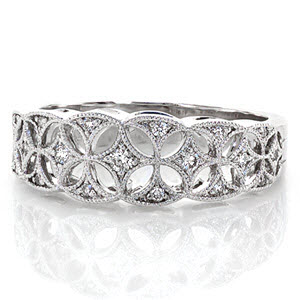 Unique pierced openwork captures the allure of a vintage era. Within the intricate star burst patterns a total 0.25 carats of round cut diamonds are set. Creating an interlocking design with alternating triangle crescents, the 14k white gold band is finished with milgrain detail.