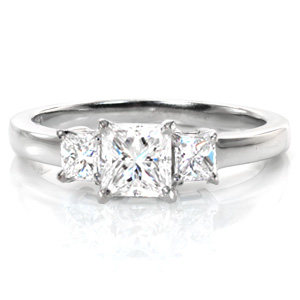 A timeless three stone design, our Princess Classic showcases a three-quarter carat princess cut diamond. The side diamonds are perfectly proportioned to accent the center stone, adding more delightful sparkle. The straight basket settings and the polished band complement the sharp angles of the diamonds beautifully. 