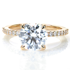 A 2 carat round is set simply atop a charming shared prong band with more brilliant diamonds spanning half way around the ring. This classic style delivers lots of sparkle, and it is designed so that any wedding band design will sit flush against it.