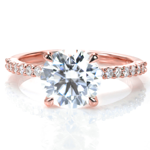 A 2 carat round is set simply atop a charming shared prong band with more brilliant diamonds spanning half way around the ring. This classic style delivers lots of sparkle, and it is designed so that any wedding band design will sit flush against it.