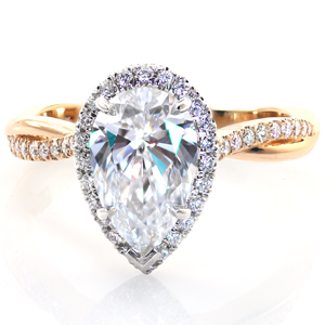 An impressive 2 carat pear shaped diamond is the star of this custom engagement ring. Set in gleaming platinum and surrounded by a delicate diamond halo, the center setting rests atop a warm, 14 karat yellow gold twisted band. French pavé set diamonds are intertwined with high polished metal for a lovely contrast.