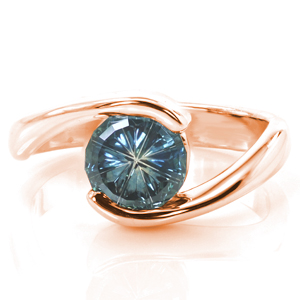 A stunning, uniquely cut sapphire is the star of this elegant design. Graceful curves of high polished metal encase the stone in a half bezel setting, allowing light in through both sides. The simplicity of the setting is the perfect complement to the mesmerizing stone. 