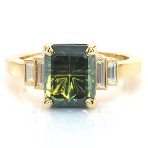 Timeless elegance is the hallmark of this design. A uniquely cut green sapphire is held in four rounded prongs. Bezel set baguette side diamonds step down from the center stone into a high polished band. Hand applied milgrain detail outlines the side diamonds for just a touch of vintage flair.