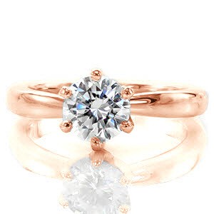 The symmetrical six prongs of the Bombe Solitaire create a lovely outline of the 1.00 carat round brilliant diamond. The uniform band has a subtle taper towards the top of the ring drawing the eye ever-so-slightly to the center stone. Each edge glistens from the high polish finish of the 14k white gold metal.  