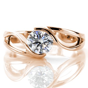 This sophisticated solitaire design features a 0.75 carat round brilliant cut diamond. The lustrous band creates a sense of flowing movement and embraces the center stone. The open pockets between the split shank keep the design delicate and maintain the fluid aesthetic.