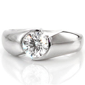 This contemporary mounting features a 0.75 carat round brilliant cut diamond set within a half bezel design. The seamless mounting appears to envelop the center stone in a beautiful high polish finish. The design features two flush set diamonds along the side, adding a decorative touch. 