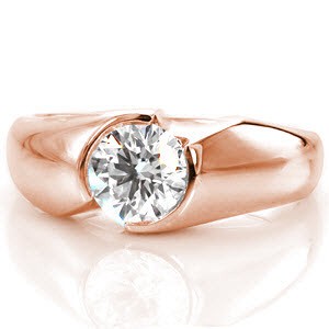 This contemporary mounting features a 0.75 carat round brilliant cut diamond set within a half bezel design. The seamless mounting appears to envelop the center stone in a beautiful high polish finish. The design features two flush set diamonds along the side, adding a decorative touch. 
