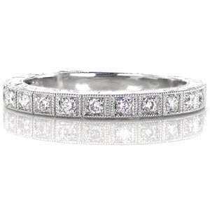 The True Love wedding band is crafted in 14k white gold and features prong set round cut diamonds totaling 0.15 carats. A single row of milgrain frames each diamond. The sides of the ring are accented with a hand engraved single wheat pattern. The lower sections of the top of the band feature a double wheat pattern.