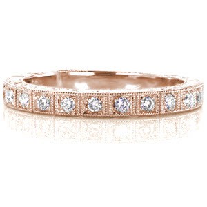 The True Love wedding band is crafted in 14k white gold and features prong set round cut diamonds totaling 0.15 carats. A single row of milgrain frames each diamond. The sides of the ring are accented with a hand engraved single wheat pattern. The lower sections of the top of the band feature a double wheat pattern.