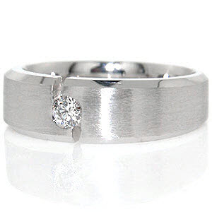 Dallas is a modern wedding band created in 14k white gold. The design features a 0.19 carat round brilliant diamond flush set between a unique notched channel. A matte finish center is contrasted by high polish beveled edges that give this contemporary band a distinguished look. 