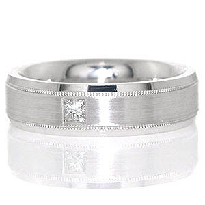 Atlanta is a sophisticated band shown in 14k white gold. A 0.15 carat princess cut diamond is flush set in the middle of the band for appeal. The beveled band is detailed with three textures: high-polished beveled sides, a matte finished middle, and two grooves that have a reversed milgrain texture.