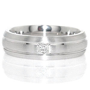 Knox Jeweler's Miami is a unique contemporary gent's band featured in 14k white gold. Two grooves evenly spaced, run parallel along the design in a high polish finish. The raised surface is given a matte finish, giving depth to the channels. A 0.15 carat princess cut is fashioned in center of the band for interest.   