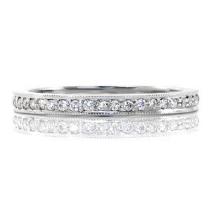 This elegant wedding band is detailed with a row of micro pavé on the top. The diamonds equal a total of .18 carats and are edged by milgrain texture to separate the setting from the high polish of the band. The smooth sides make this ring ideal for pairing with an engagement ring. 