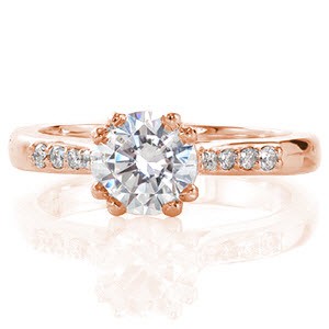 Delightful in its simplicity, this ring focuses all your attention on the 1.00 carat round center diamond. The design is made intriguing by the subtle details it incorporates: the center stone has double prongs and there is a bezel set surprise diamond on each side under the center stone. 