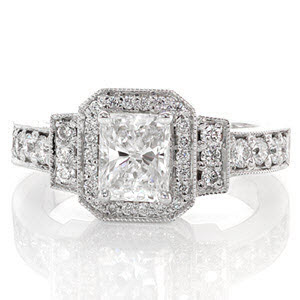 A magnificent design embellished in micro pavé, this ring is featured with a 1.00 carat radiant cut center diamond. The center stone is surrounded by a rectangular halo with clipped corners, a bar on each side, and finally the band. The side diamonds increase in size from the halo to the band. 