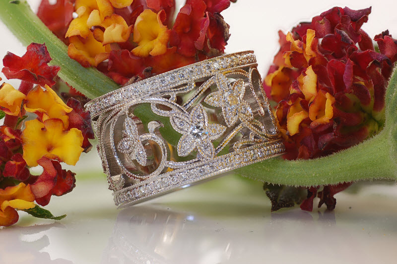 Wide band ring in Omaha with nature inspired patterns between diamonds bands.